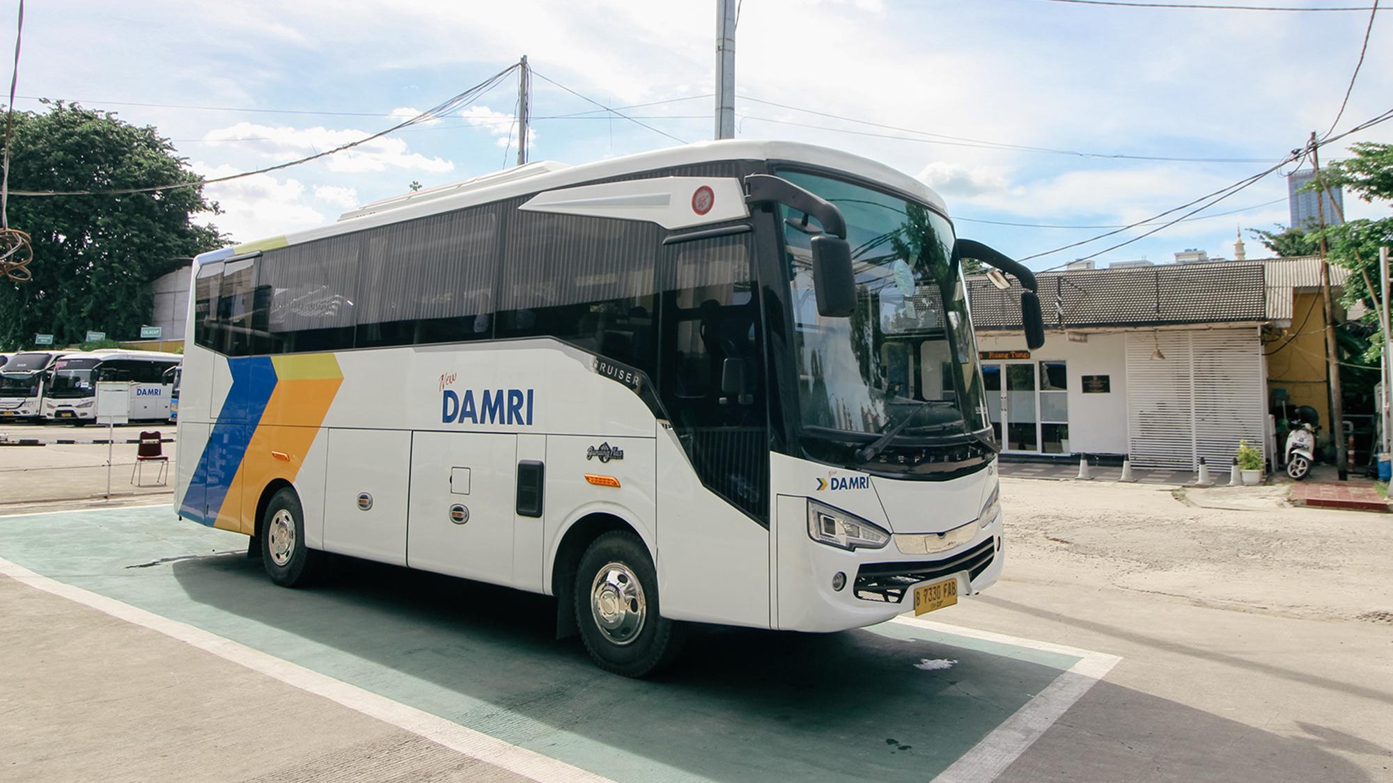 Bus Damri di terminal dengan latar bandara, menunjukkan layanan transportasi darat jarak jauh